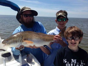Blue Smith, center, caught this fine 26 inch redfish off Hardy Point while fishing with Dan and Andrew Deaver and Luke Cocke. They also scored trout, Spanish mackerel and flounder. 